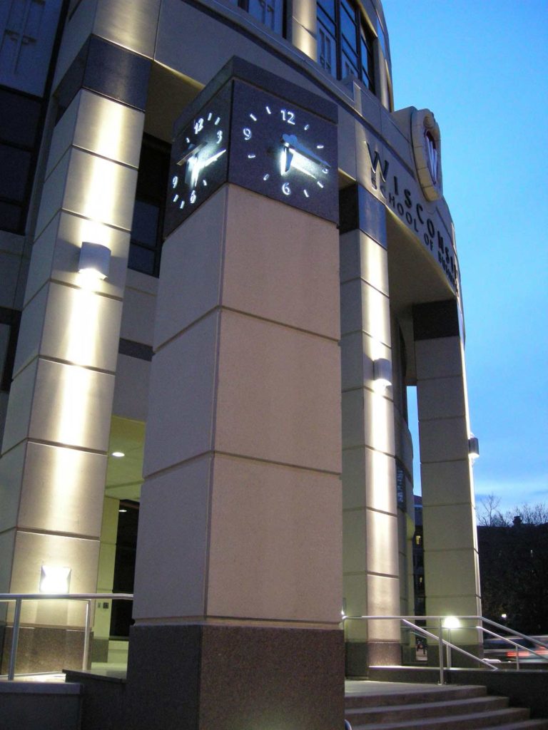 Dusk at the polished Granite clock tower at Granger Hall University of Wisconsin with an illuminated Skeletal silhouette marker stainless steel clock by Lumichron