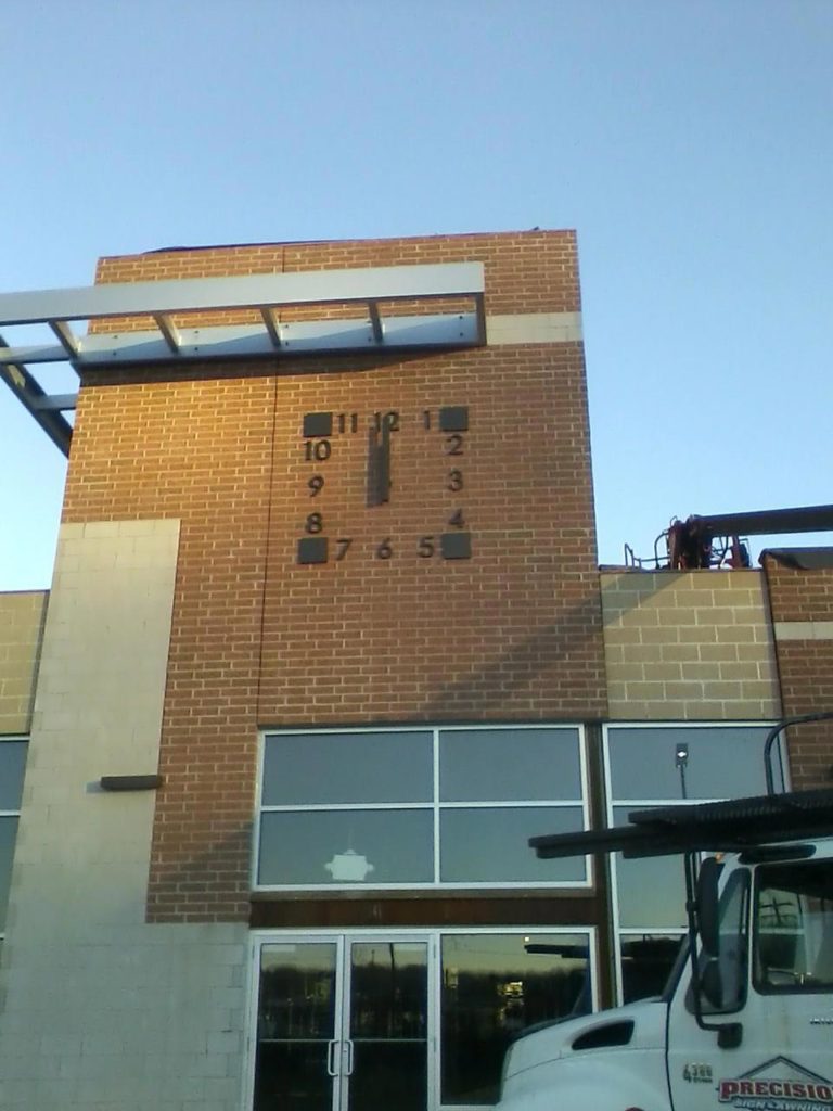 Sunrise on a skeletal silhouette marker shopping center square clock on brick by Lumichron