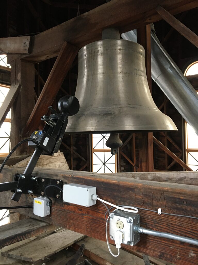 Bronze bell with an electromagnetic bell striker in a belfry clock tower at the Fergus County Courthouse