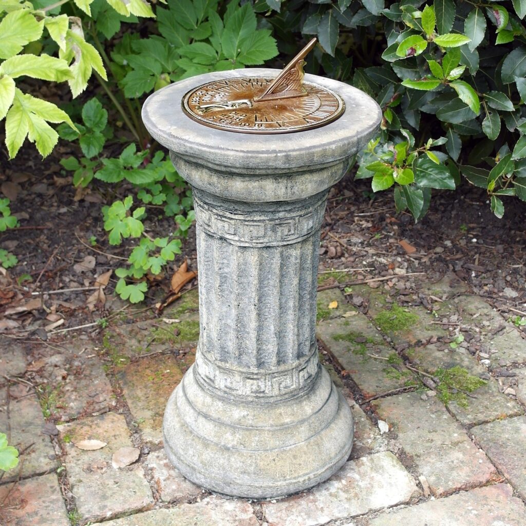 A sundial in the garden is decorative and useful. A cast bronze sundial on a stone column, in the garden on a brick patio
