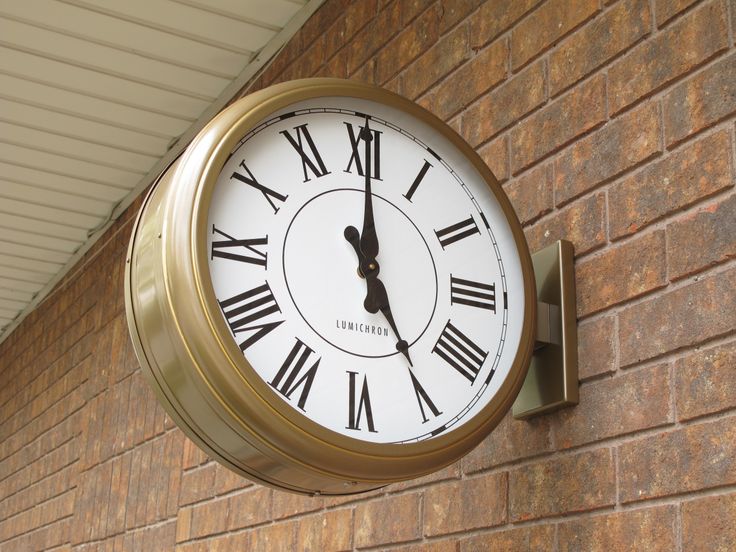 Lumichron bracket clock mounted to brick wall with gold custom case finish